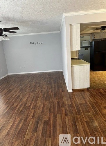 A living room with a wooden floor and a ceiling fan.
