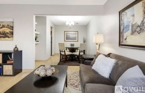 A living room with a brown couch and a painting on the wall.