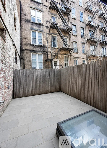 A patio with a glass table and a wooden fence.