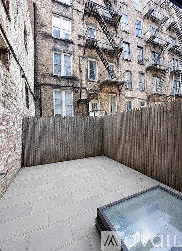A patio with a glass table and a wooden fence.