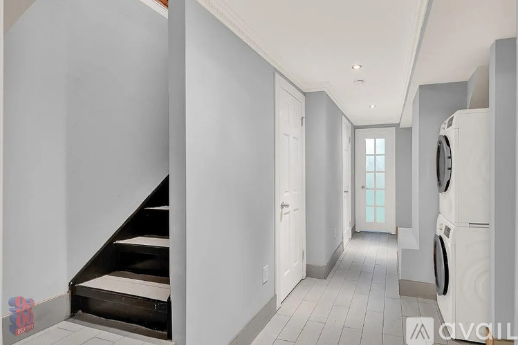 A hallway with a washing machine on the right side.