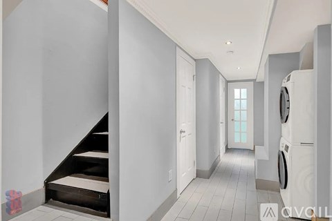 A hallway with a washing machine on the right side.