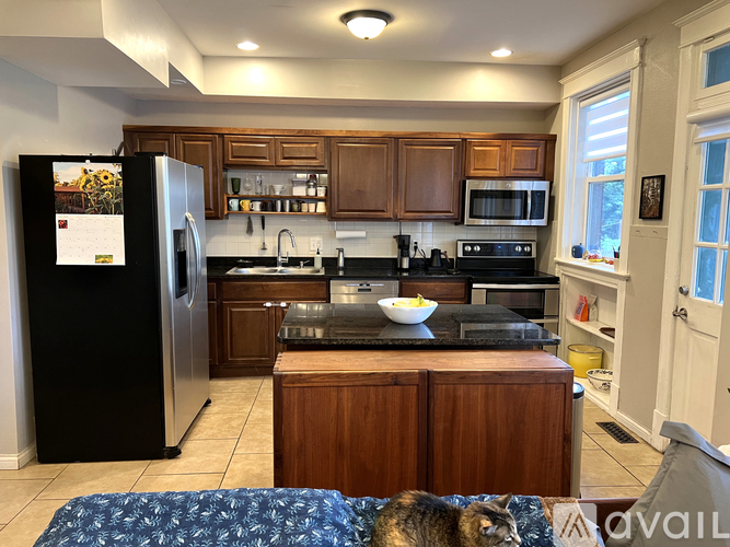 A kitchen with wooden cabinets and a black refrigerator.
