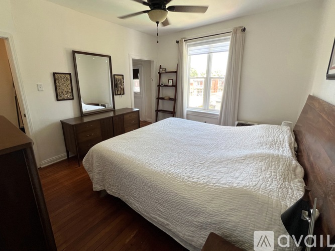 A bedroom with a large bed and a dresser with a mirror.