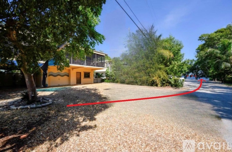 A yellow house with a red line drawn on the driveway.