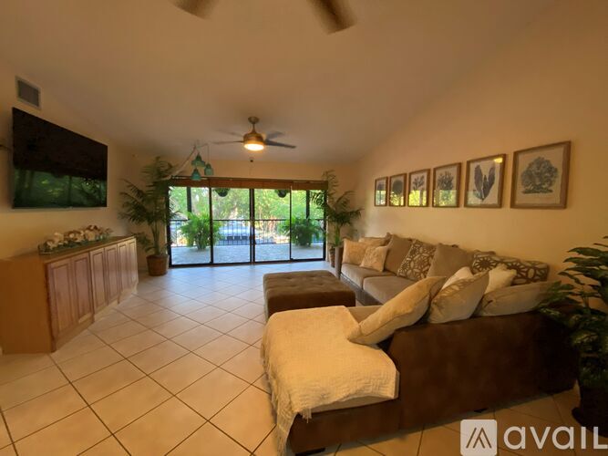 A living room with a brown couch and a ceiling fan.