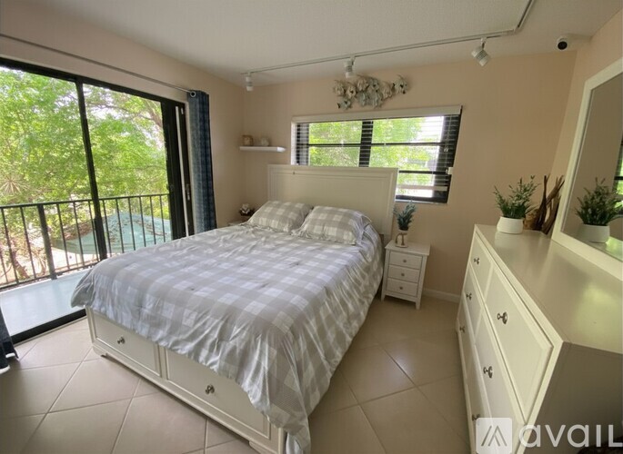 A bedroom with a large bed and a balcony with a view of trees.