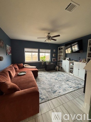 A living room with a red couch and a ceiling fan.