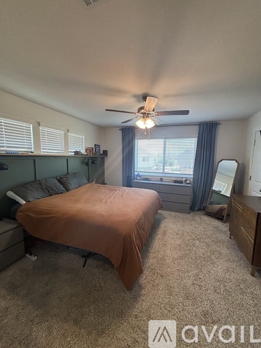 A bedroom with a bed, dresser, and window.