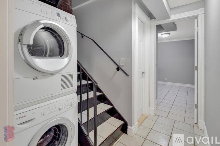 A white washing machine is placed next to a staircase.