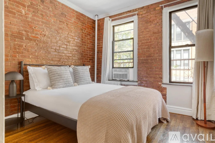 A bedroom with a brick wall and a bed with a white comforter.