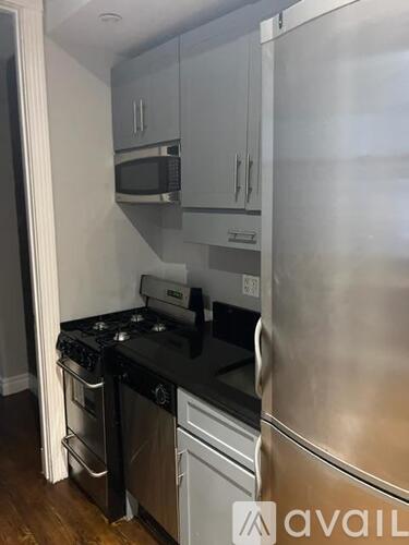 A kitchen with a stainless steel refrigerator, microwave, and oven.