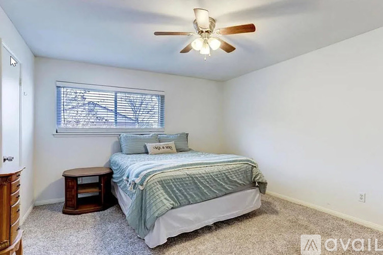 A bedroom with a bed, a small table, and a ceiling fan.