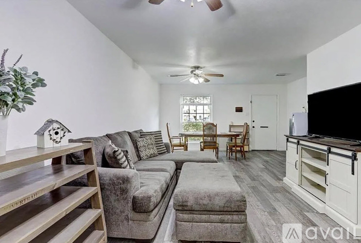 A living room with a grey couch and a wooden shelf.