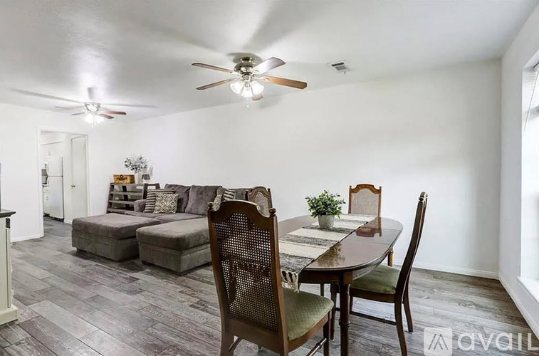 A dining room with a table set for two and a couch.