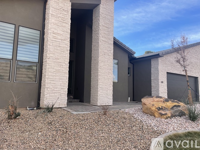 A modern house with a stone pillar entrance and a rock in front.