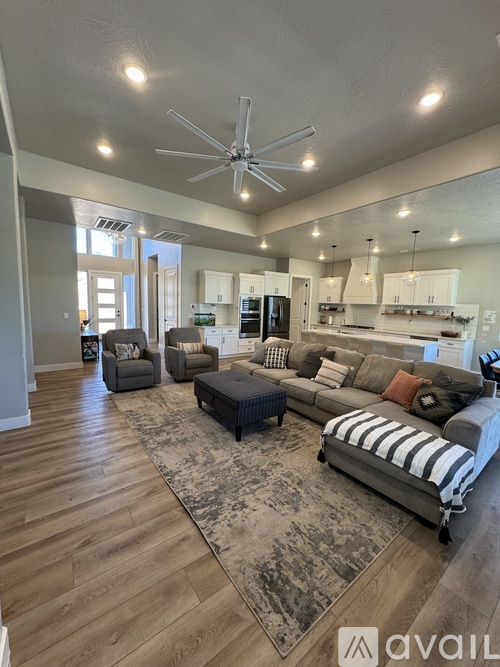 A spacious living room with a grey sofa and a rug.