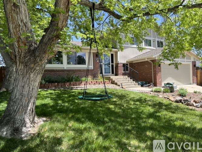 A swing set is in the front yard of a house.
