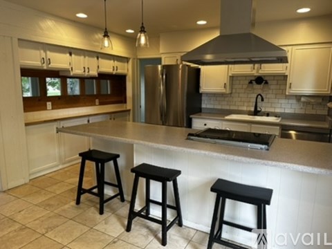 A kitchen with a white counter and black stools.