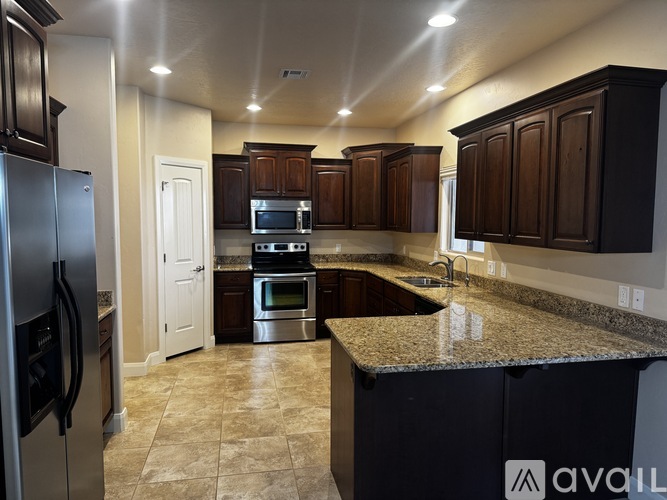 A kitchen with dark brown cabinets and a granite countertop.