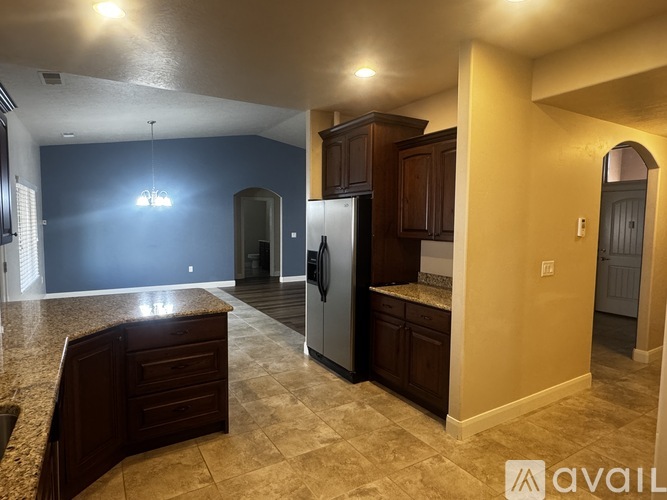 A kitchen with a sink, refrigerator, and cabinets.