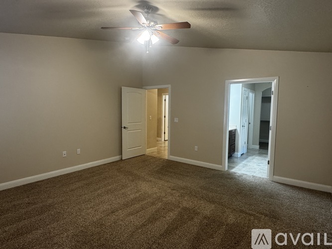 A room with a carpeted floor and a ceiling fan.