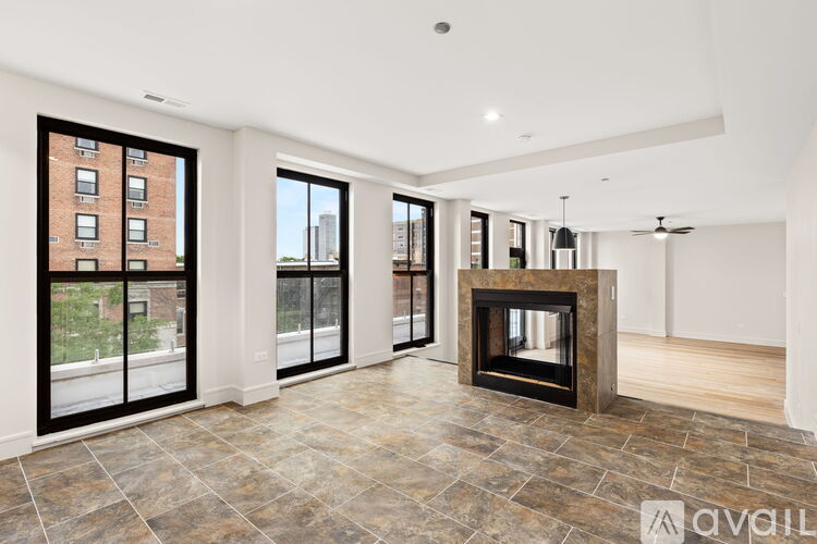 A large, empty living room with a fireplace and a view of a city skyline.