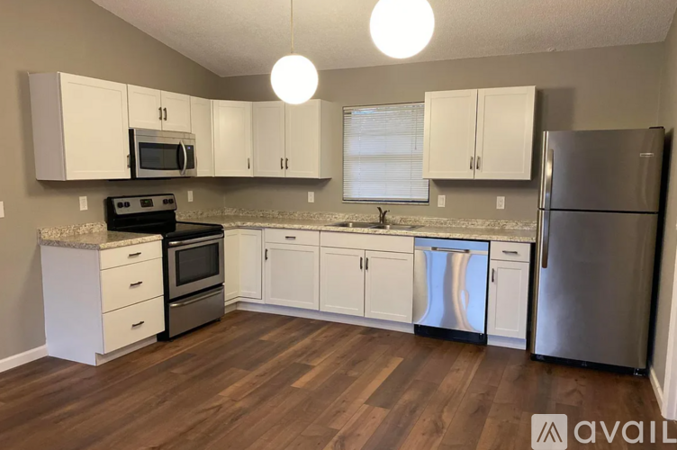 A kitchen with white cabinets and a wooden floor.