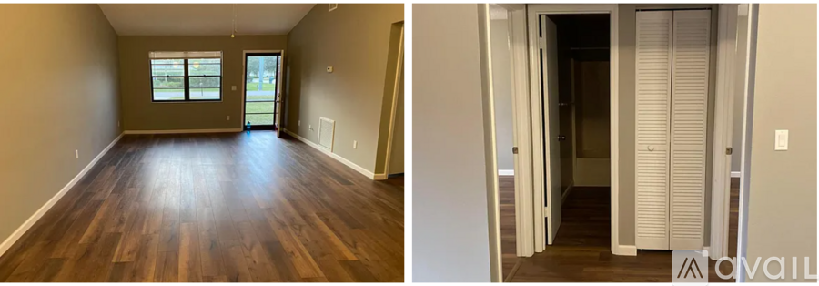 A room with wooden floors and a door leading to another room.