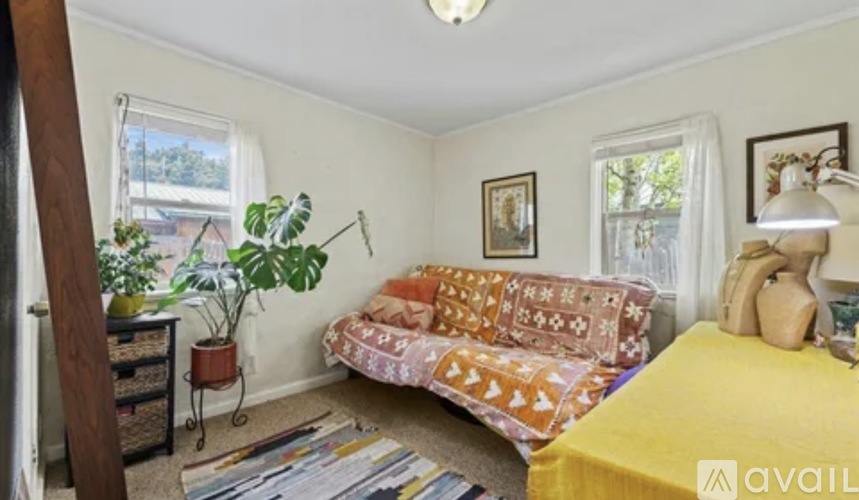 A living room with a yellow bed and a couch with a patterned cover.