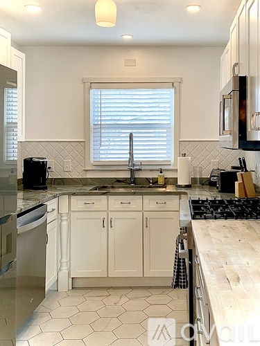 A kitchen with white cabinets and a black stove top.