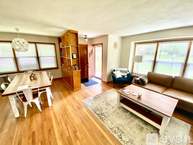 A living room with a brown couch, a wooden coffee table, and a dining table with chairs.