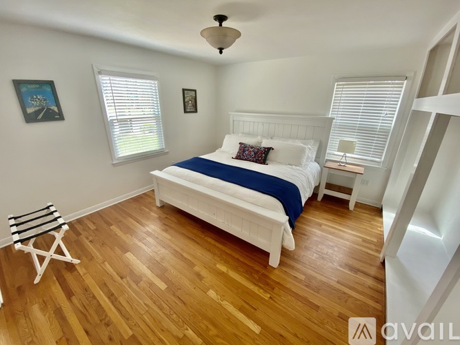 A bedroom with a white bed and wooden floors.