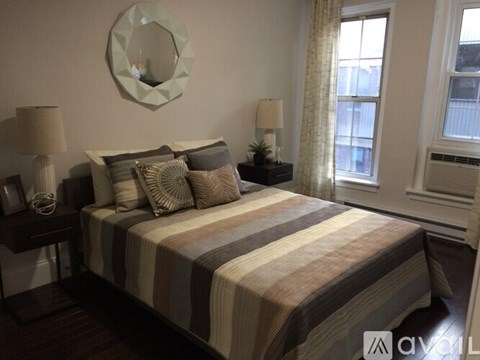 A bedroom with a bed, two lamps, and a mirror on the wall.