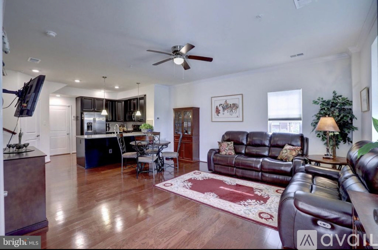 A living room with a brown leather couch and a wooden floor.