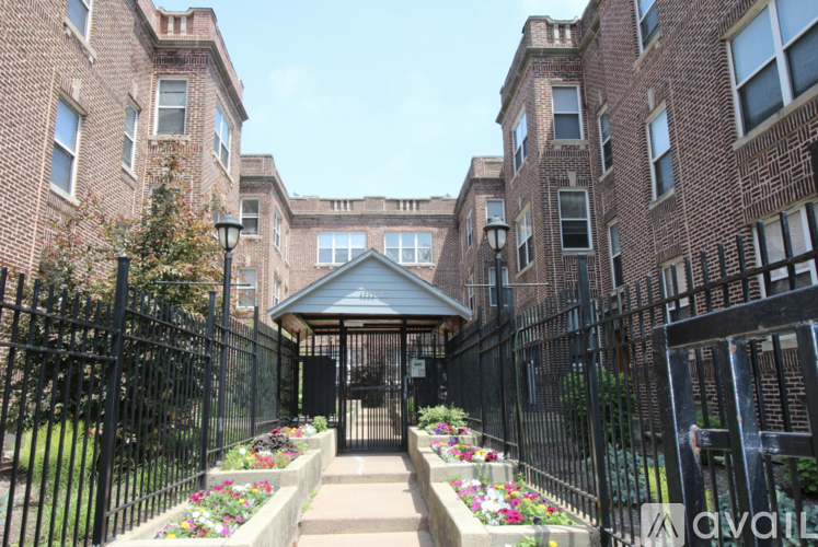 A black wrought iron fence surrounds a brick building with a small gazebo in the center.