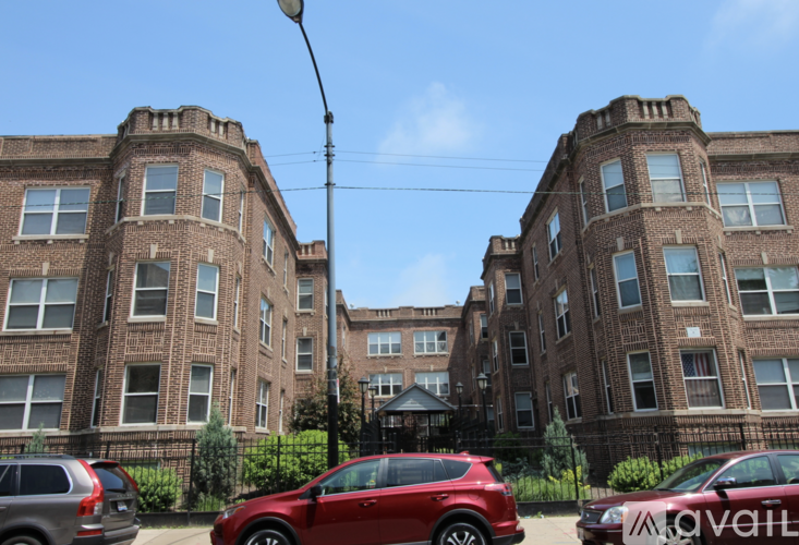 A red car is parked in front of a brick building.