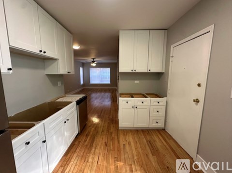 A kitchen with white cabinets and wooden floors is available.