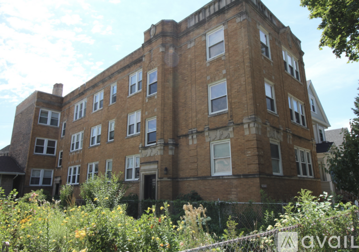 A large brown building with many windows is surrounded by greenery.