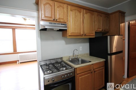 A kitchen with wooden cabinets and a stainless steel refrigerator.