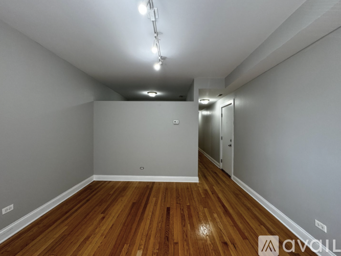A room with wooden floors and a door on the right side.