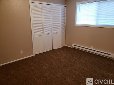 A room with brown carpet and a window with blinds.