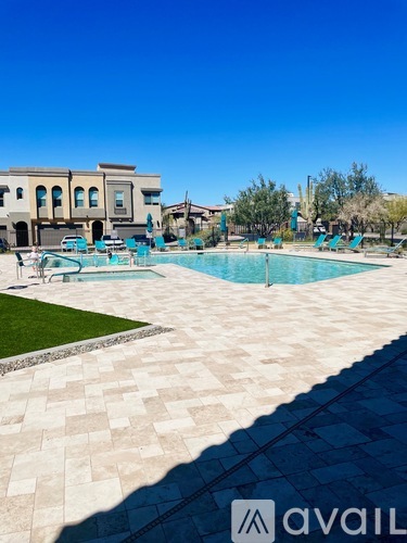 A large swimming pool surrounded by a tiled patio and lounge chairs.