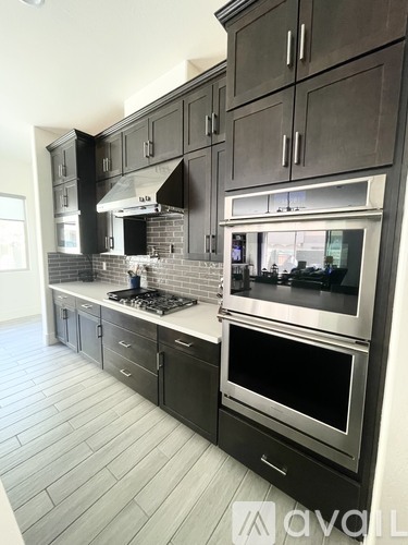 A kitchen with dark cabinets and a stainless steel oven.