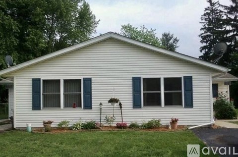 A white house with a grey roof and a black window frame.