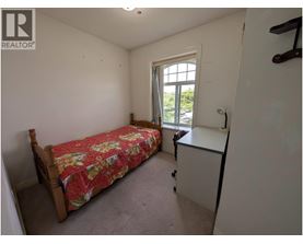 A bedroom with a bed, a window, and a small desk.