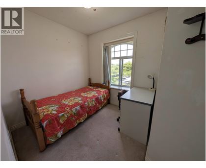 A bedroom with a bed, a window, and a small desk.