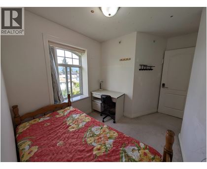 A bedroom with a bed, desk, and chair.