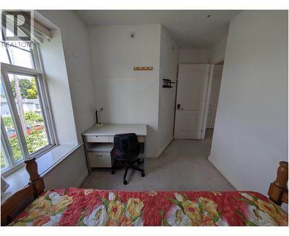 A bedroom with a bed, desk, and chair.