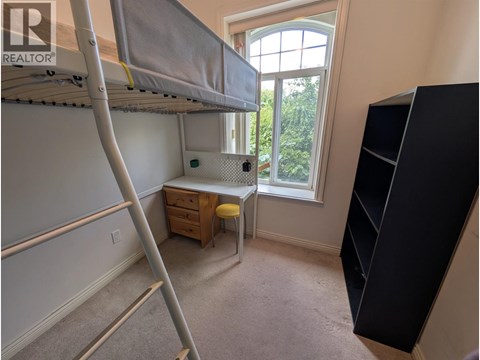 A bedroom with a bunk bed and a desk with a window.